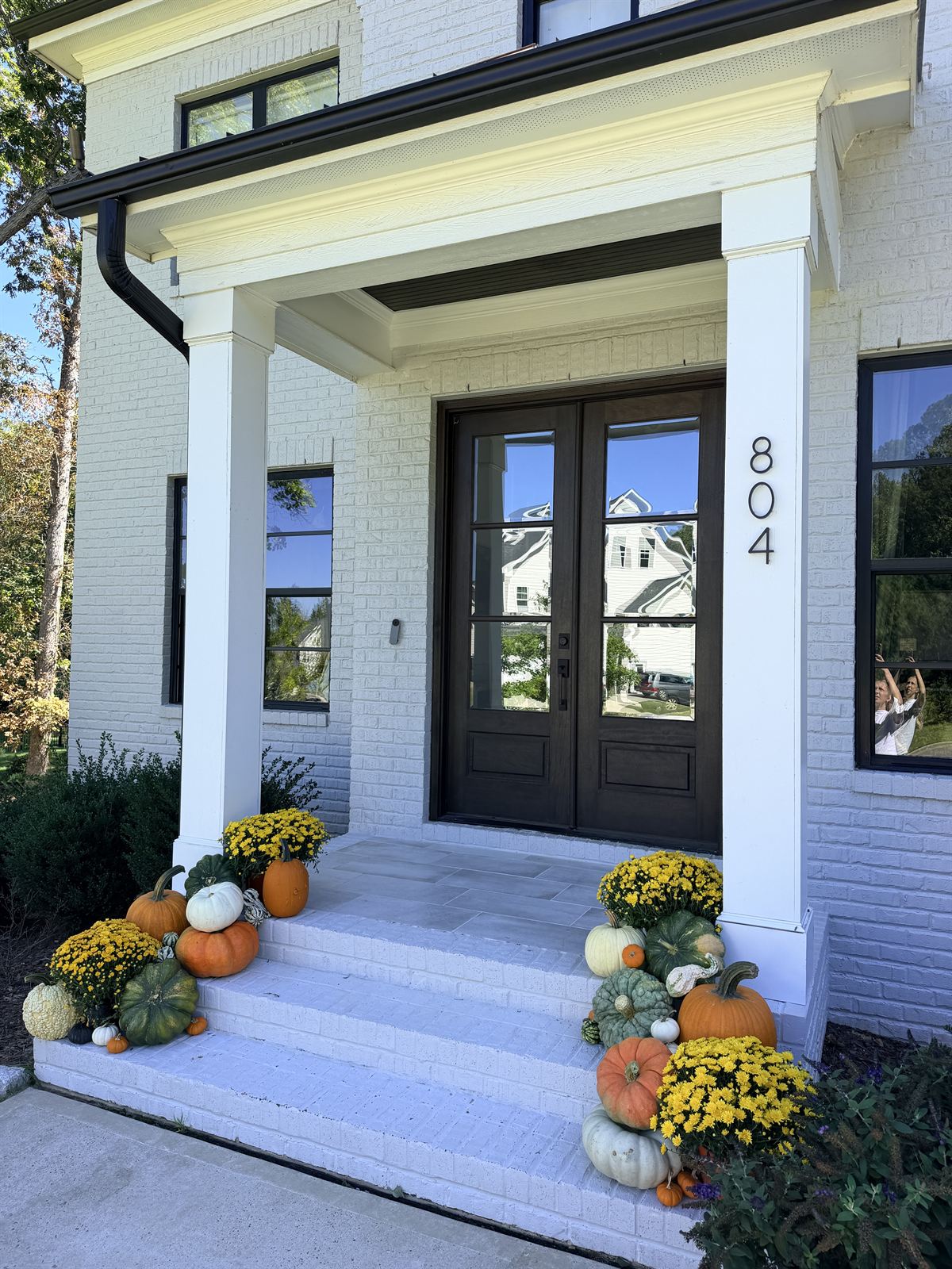White brick porch steps with yellow mums, green and orange pumpkins, Cary NC area