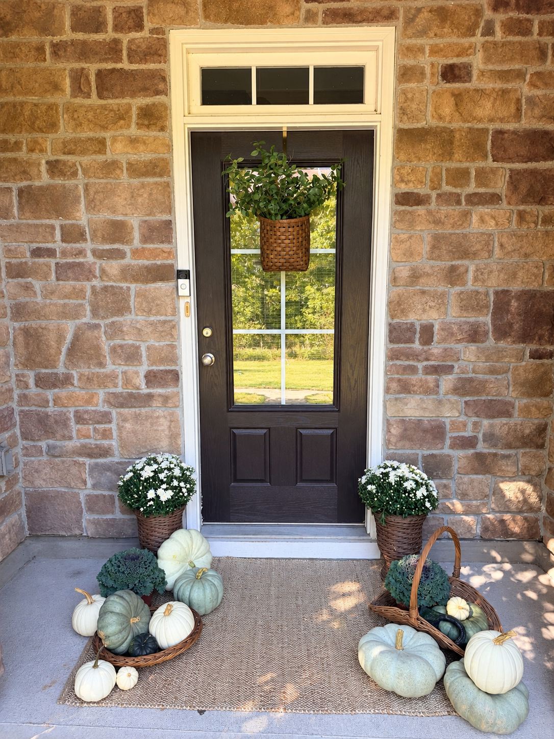 Stone entry with a dark front door, white mums, ornamental cabbages and baskets of sage and white heirloom pumpkins, Triangle NC