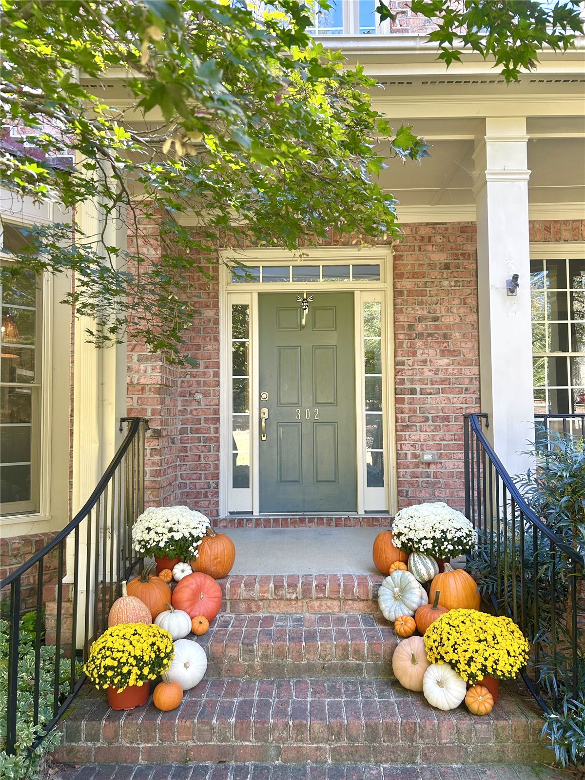 Fall doorstep display with white ghost pumpkins and mums